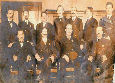 Look at the photograph of Immigrant Inspectors at Ellis Island.

Two rows of Ellis Island inspectors