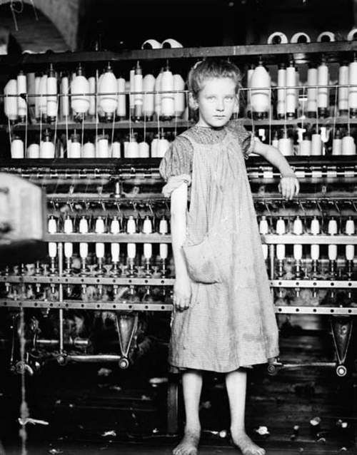 Analyze this picture of a 12-year-old girl working in a mill. what safety hazards do you see in her