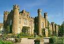 The majestic castle, surrounded by green foliage, stood proudly with turrets pointing skyward. which