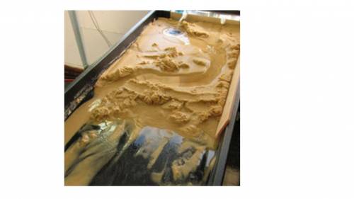 This is an image of a stream table modeling how water can change surface features of Earth. Which of